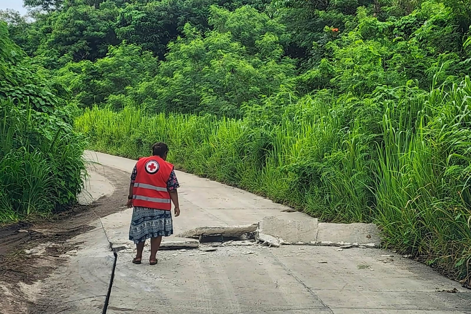 In this photo released by Vanuatu Red Cross Society, a Red Cross volunteer inspects a damaged road in Efate, Vanuatu, Thursday, Dec. 19, 2024, following a powerful earthquake that struck just off the coast of Vanuatu in the South Pacific Ocean. (Vanuatu Red Cross Society via AP)