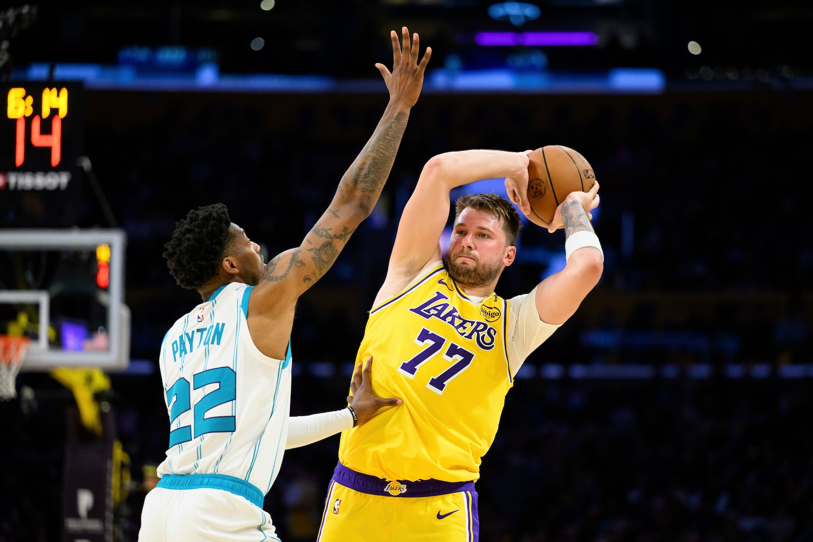 Los Angeles Lakers guard Luka Doncic (77) looks to pass the ball while under pressure from Charlotte Hornets guard Elfrid Payton (22) during the second half of an NBA basketball game Wednesday, Feb. 19, 2025, in Los Angeles. (AP Photo/William Liang)