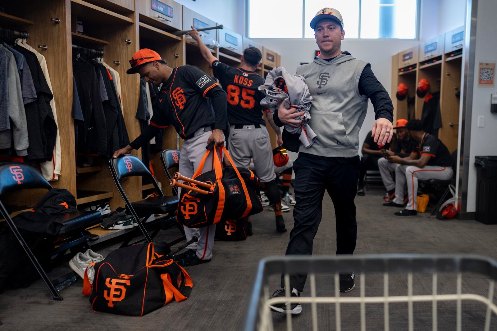 San Francisco Giants clubhouse attendant Riley Halpin gathers dirty clothes in the clubhouse after spring training baseball practice at the team's facility, Monday, Feb. 17, 2025, in Scottsdale, Ariz. (AP Photo/Carolyn Kaster)