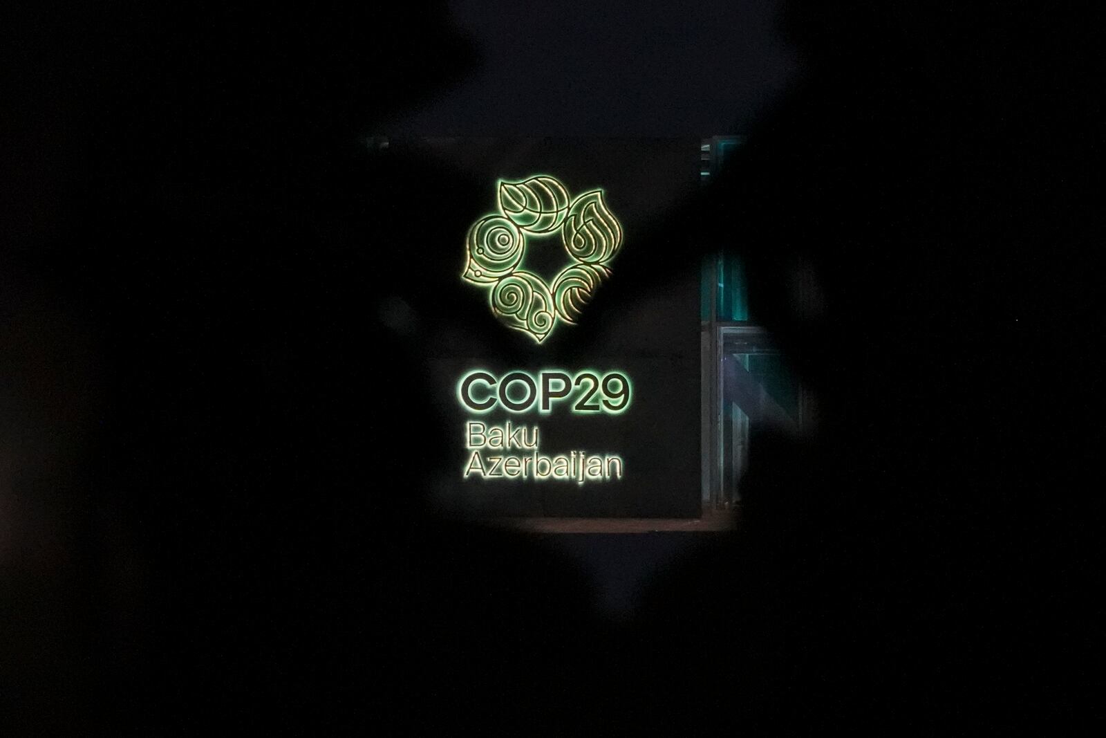 The logo for the COP29 U.N. Climate Summit is visible through artwork outside the venue, Tuesday, Nov. 12, 2024, in Baku, Azerbaijan. (AP Photo/Peter Dejong)