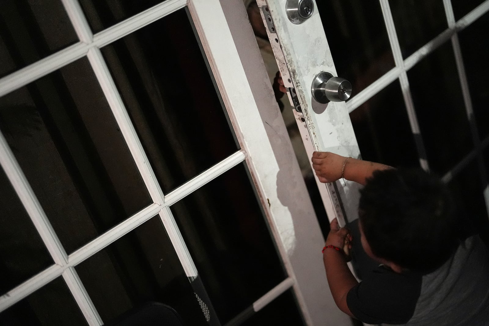 A young child pulls open a door as Nora Sandigo, who runs a non-profit dedicated to supporting immigrant families, educates undocumented migrants on their legal rights and options to prepare their families in case a parent were to be detained or deported, Friday, Jan. 17, 2025, in Homestead, Fla. (AP Photo/Rebecca Blackwell)