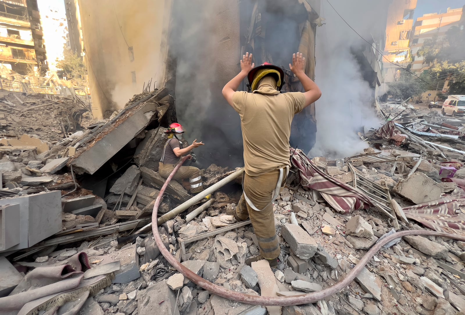 Firefighters try to extinguish a fire as smoke rises from a destroyed building that was hit in an Israeli airstrike in Dahiyeh, in the southern suburb of Beirut, Lebanon, Thursday, Nov. 14, 2024. (AP Photo/Hussein Malla)