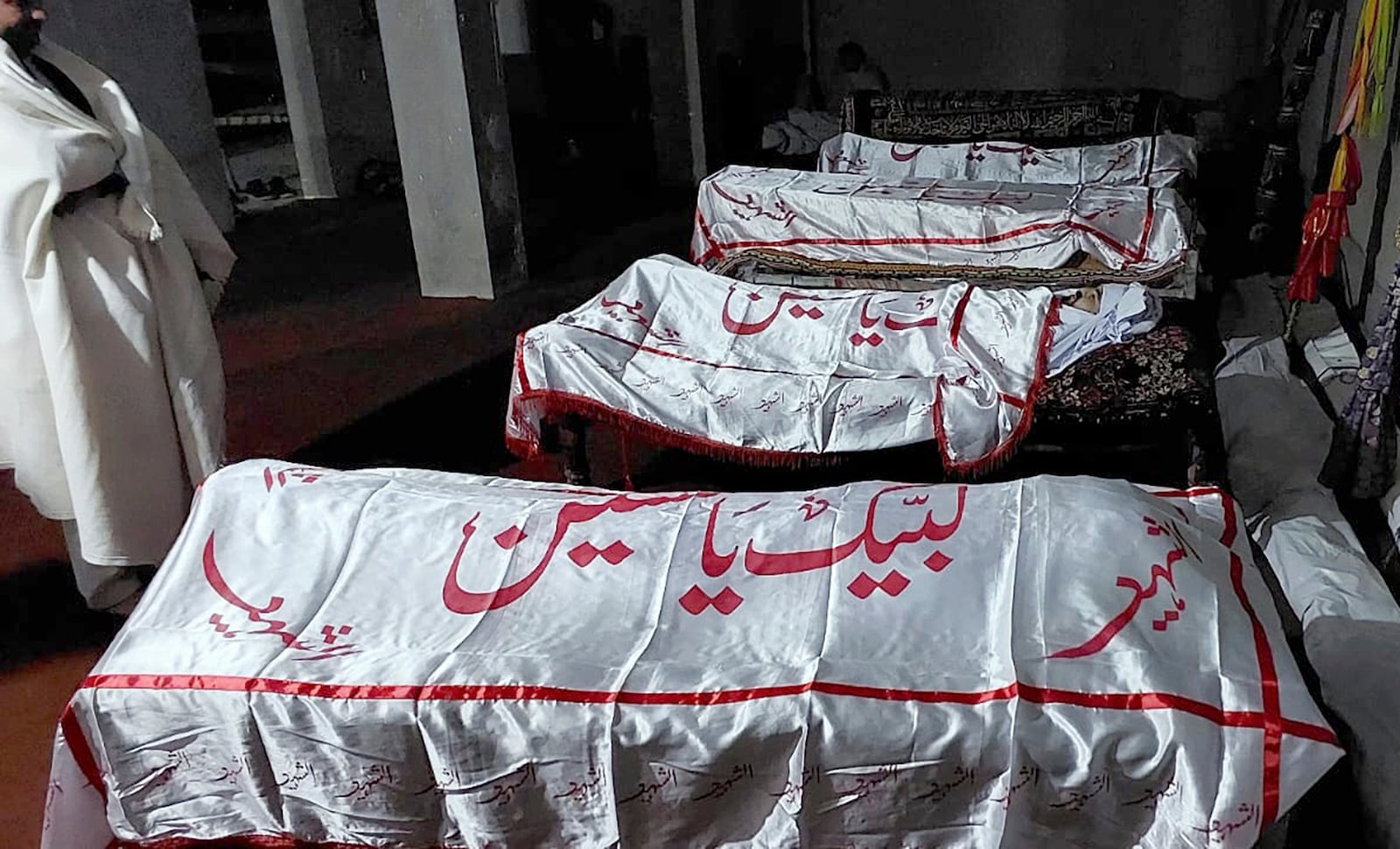 A mourner stands beside the bodies of the victims. who were killed in a gunmen firing incident, before their funeral prayer, in Parachinar, main town of Kurram district of Pakistan's northwestern Khyber Pakhtunkhwa province, Friday, Nov. 22, 2024. (AP Photo/Hussain Ali)