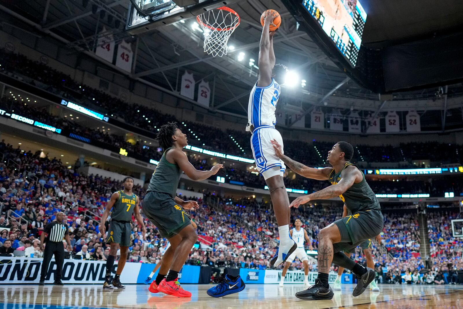 Duke center Patrick Ngongba II loses his shoe as he shoots between Baylor guard Robert Wright III and guard Langston Love, right, during the first half in the second round of the NCAA college basketball tournament, Sunday, March 23, 2025, in Raleigh, N.C. (AP Photo/Chris Carlson)