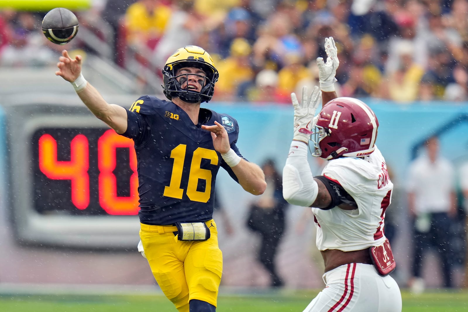 Michigan quarterback Davis Warren (16) fires a pass in front of Alabama linebacker Jihaad Campbell (11) during the first half of the ReliaQuest Bowl NCAA college football game Tuesday, Dec. 31, 2024, in Tampa, Fla. (AP Photo/Chris O'Meara)