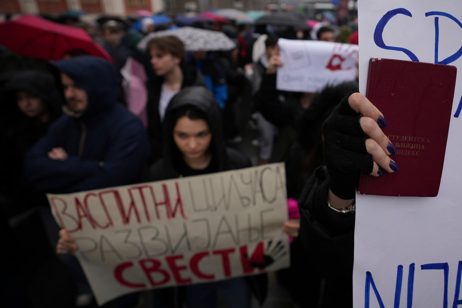 A student holds students certificate and stands in silence during ongoing protests that erupted after a concrete canopy fell last month and killed 15 people, in Belgrade, Serbia, Friday, Dec. 20, 2024. (AP Photo/Darko Vojinovic)