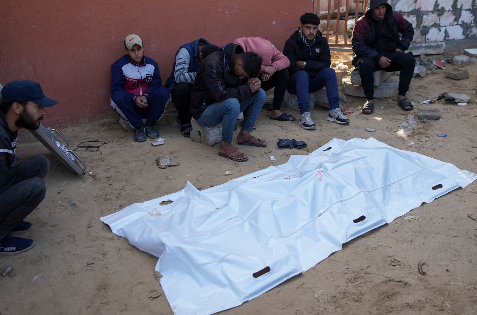 Relatives of a Palestinian killed in overnight Israeli strikes, mourn over his body outside the morgue of Nasser hospital in the Khan Younis refugee camp, southern Gaza Strip, Saturday, Jan. 4, 2025. (AP Photo/Abdel Kareem Hana)