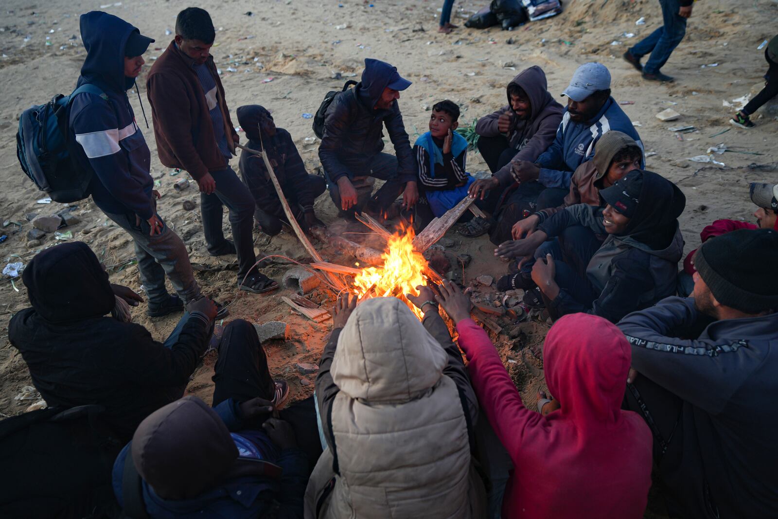 Displaced Palestinians warm themselves by a fire near a roadblock, as they wait to return to their homes in the northern part of the Gaza Strip, Sunday, Jan. 26, 2025, days after the ceasefire deal between Israel and Hamas came into effect. (AP Photo/Abdel Kareem Hana)