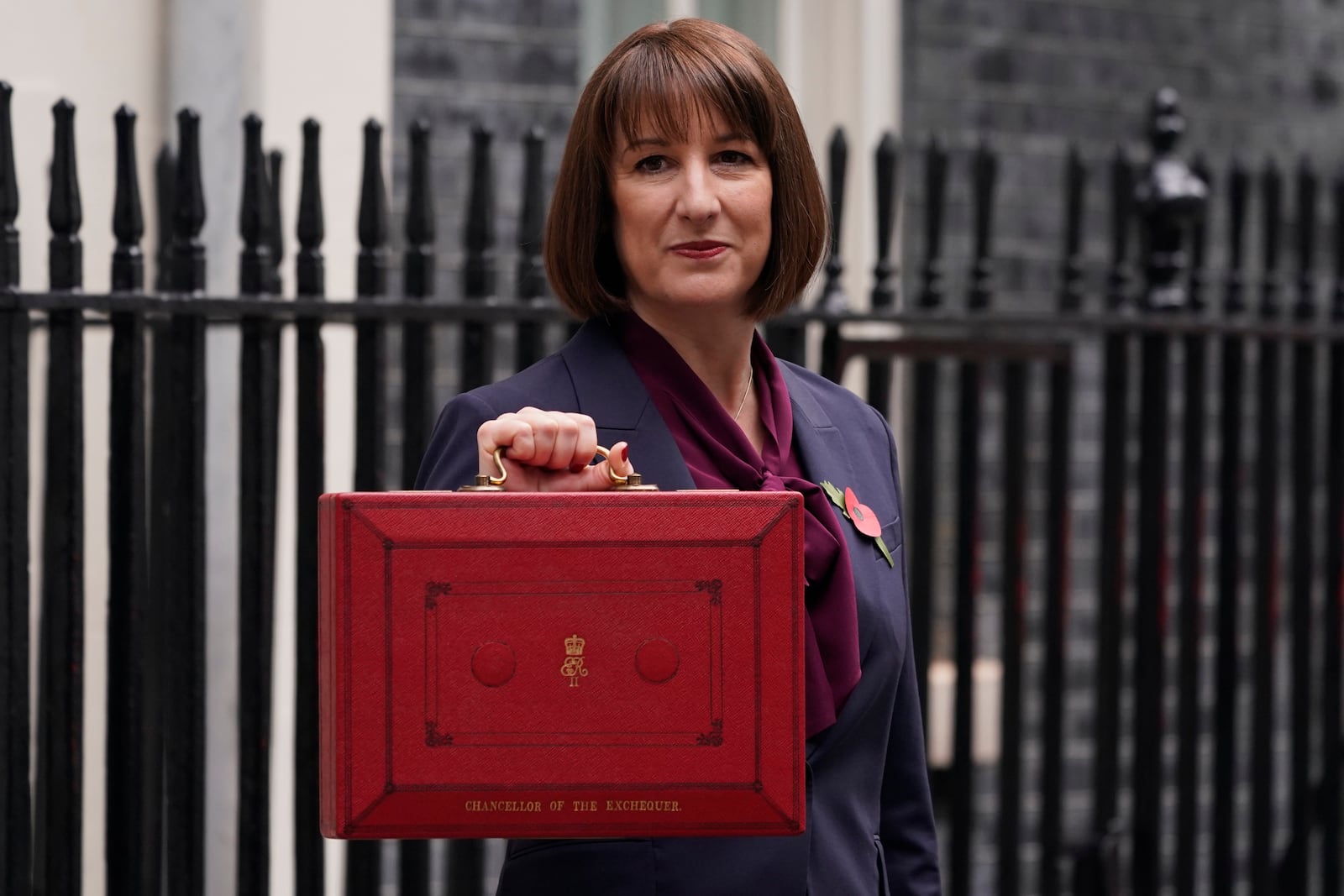 Britain's Chancellor of the Exchequer, Rachel Reeves, holds up the traditional red ministerial box containing her budget speech, as she poses for the media outside No 11 Downing Street, before departing to the House of Commons to deliver the budget in London, Wednesday, Oct. 30, 2024. (AP Photo/Alberto Pezzali)