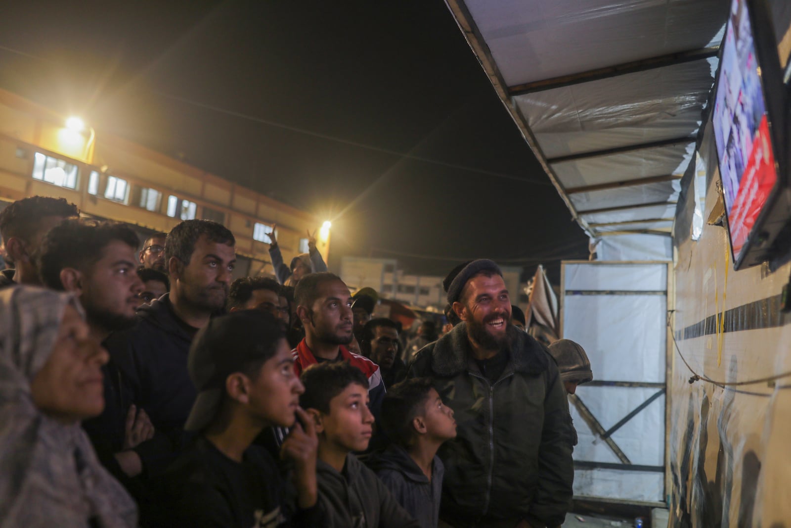 Palestinians watch TV as they await the imminent announcement of a ceasefire deal between Hamas and Israel in Khan Younis, central Gaza Strip, Wednesday, Jan. 15, 2025.(AP Photo/(AP Photo/Jehad Alshrafi)