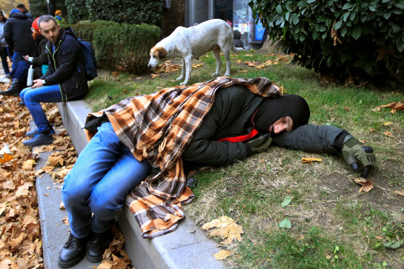 Protesters rest in a street during a rally to demand new parliamentary elections in the country, near the Parliament's building in Tbilisi, Georgia, on Monday, Nov. 25, 2024. (AP Photo/Shakh Aivazov)