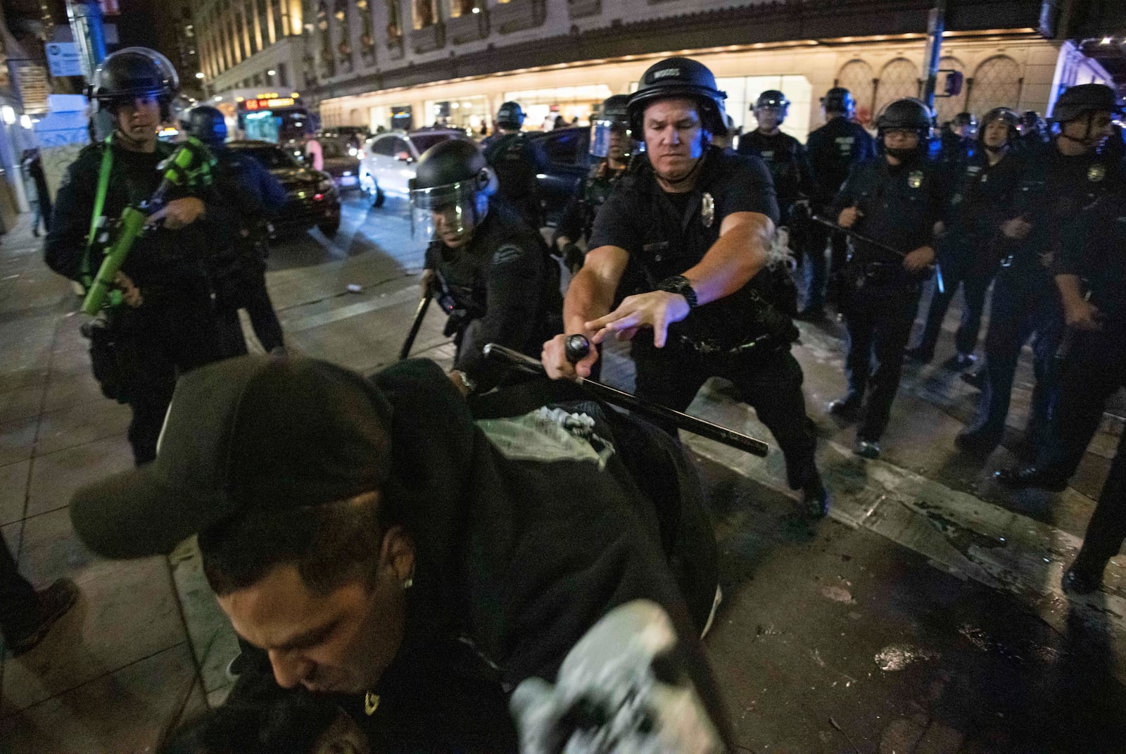 Police officers attempt to detain a man as people gather on the streets after the Los Angeles Dodgers won against the New York Yankees in the baseball World Series Wednesday, Oct. 30, 2024, in Los Angeles. (AP Photo/Ethan Swope)