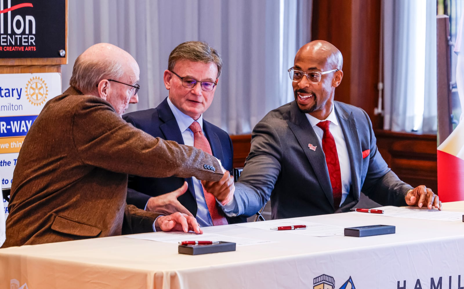 Hamilton Mayor Pat Moeller, left, John Guidugli, President and CEO of Hamilton Community Foundation, middle, and Ande Durojaiye, Dean of the College of Liberal Arts and Applied Science and Vice President of Miami Regional campuses, sign an agreement as Hamilton Community Foundation commits funding support to education as the launch of the Miami Regionals Hamilton Promise Scholarship program Thursday, Feb. 8, 2024 at Fitton Center for Creative Arts in Hamilton. NICK GRAHAM/STAFF