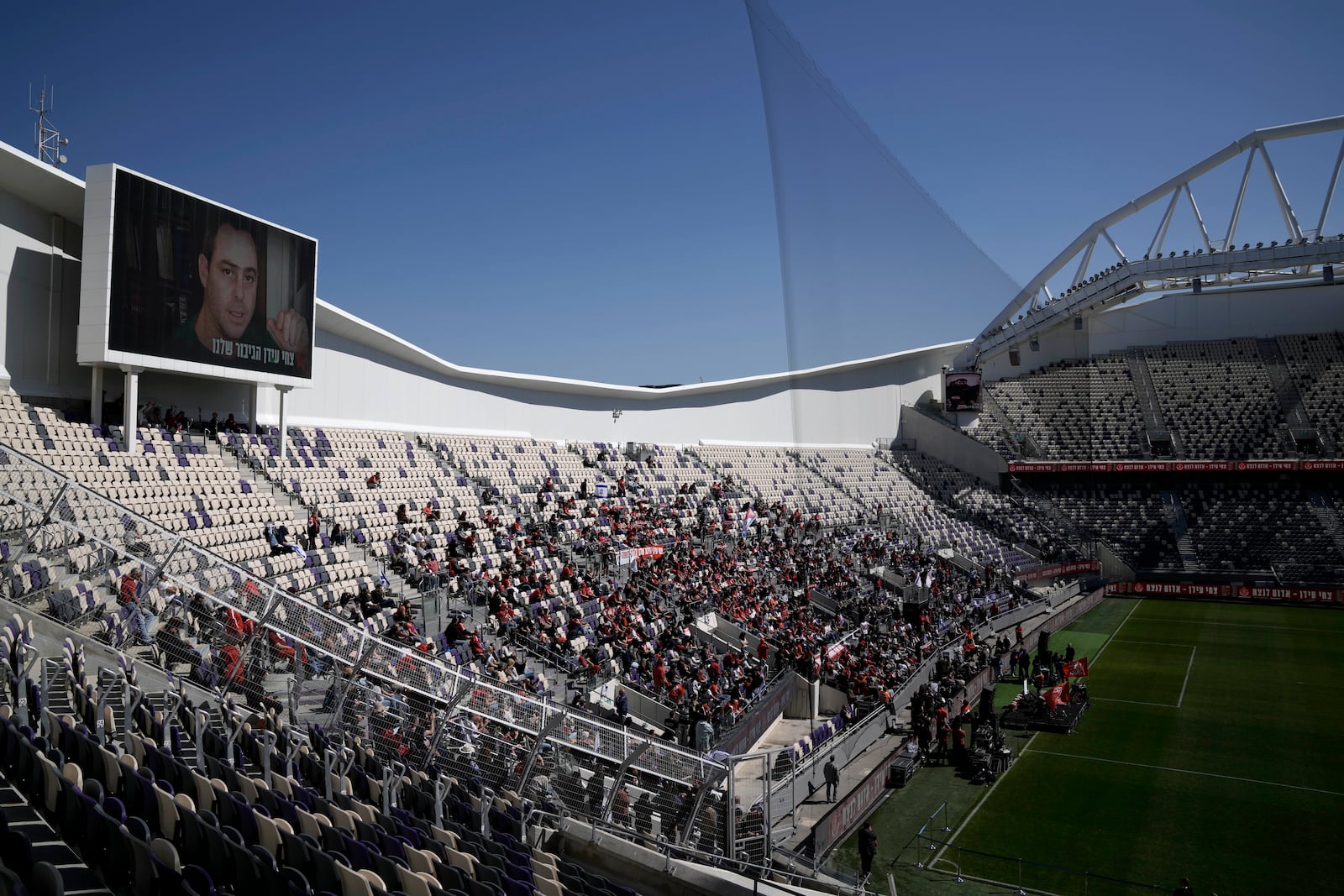 Friends, family and soccer fans attend a public memorial ceremony for slain hostage Tsachi Idan, a fan of Hapoel Tel Aviv F.C., who was killed in Hamas captivity in the Gaza Strip, at Bloomfield Stadium in Tel Aviv, Israel, Friday, Feb. 28, 2025. (AP Photo/Leo Correa)