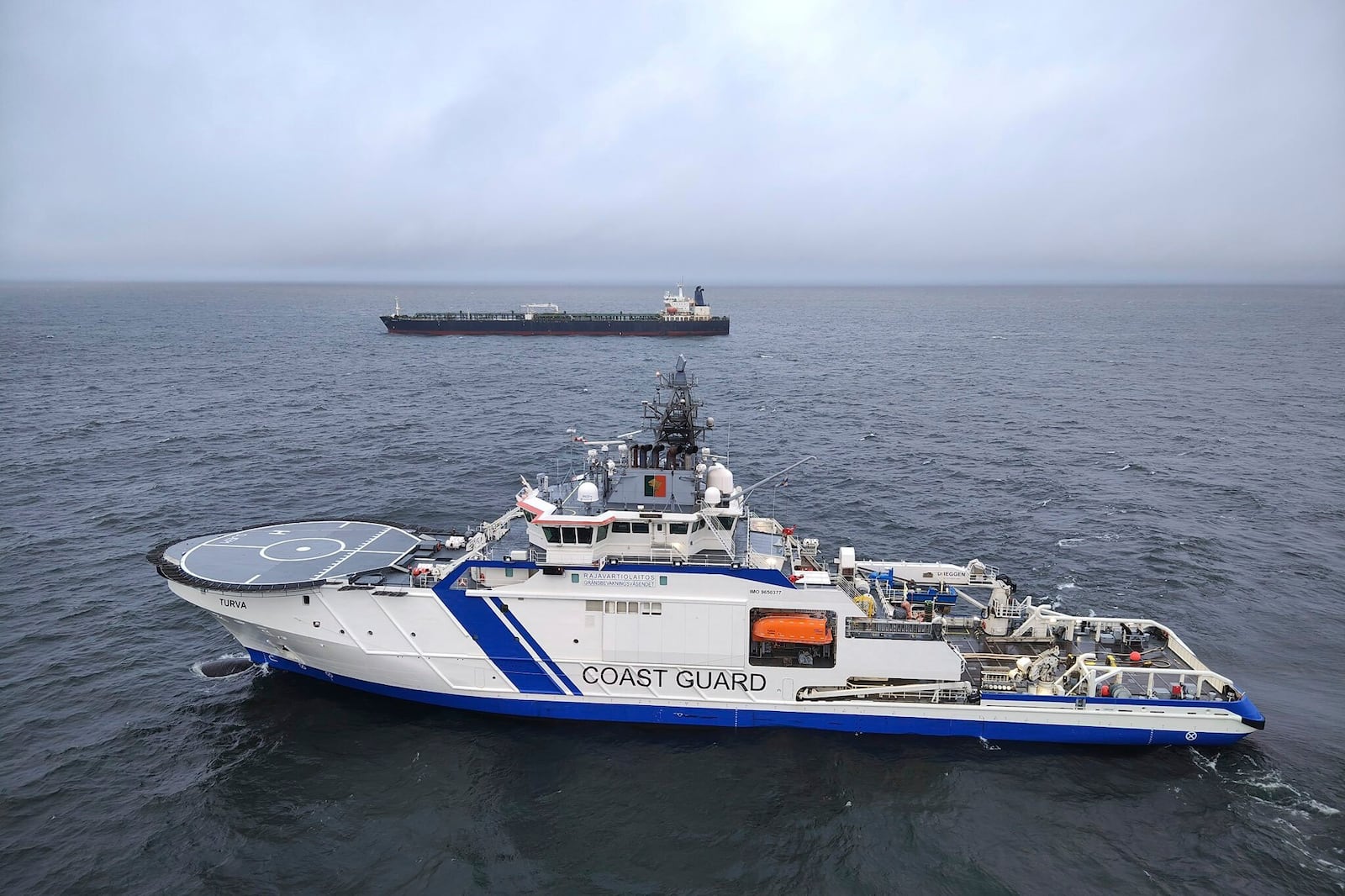 This photo provided by Rajavartiosto (Finnish Border Guard) on Thursday, Dec. 26, 2024, shows the oil tanker Eagle S, background, and the Finnish Border Guard ship Turva at sea outside Porkkalanniemi, Finland. The Eagle S was sailing at the same time in the area where the Finland-Estonia electrical link was disrupted on Wednesday. (Rajavartiosto via AP)