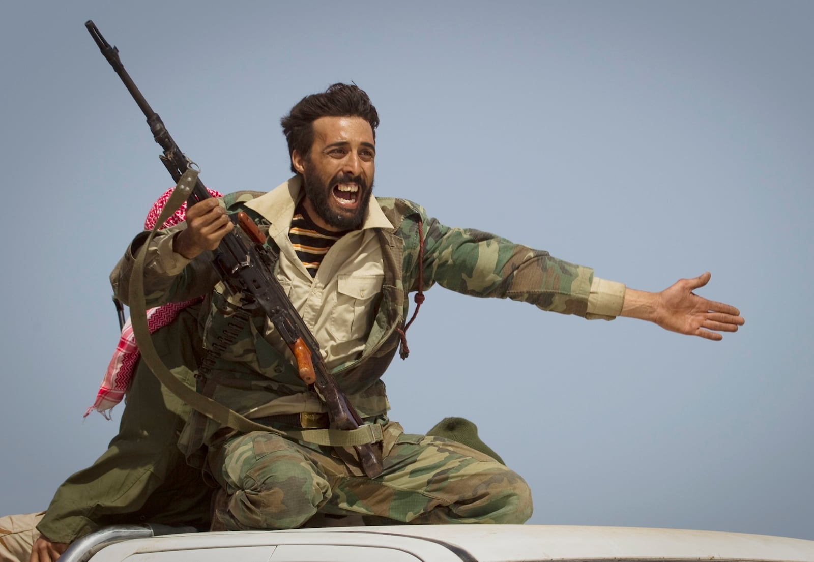 FILE - A Libyan rebel urges people to leave as shelling from Gadhafi's forces starts landing on the frontline outside of Bin Jawaad, 150 kilometers (93 miles) east of Sirte, central Libya, on March 29, 2011. (AP Photo/Anja Niedringhaus, File)