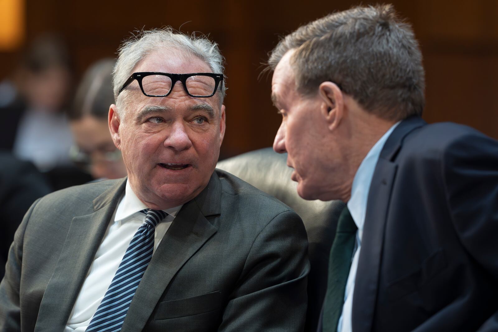 Sen. Tim Kaine, D-Va., left, and Sen. Mark R. Warner, D-Va., confer as the Senate Budget Committee works on the markup of the Fiscal Year 2025 Budget Resolution, on Capitol Hill in Washington, Wednesday, Feb. 12, 2025. Senate Republicans are vowing to move quickly on a budget plan that could pave the way for billions more in additional border security and defense spending. (AP Photo/J. Scott Applewhite)