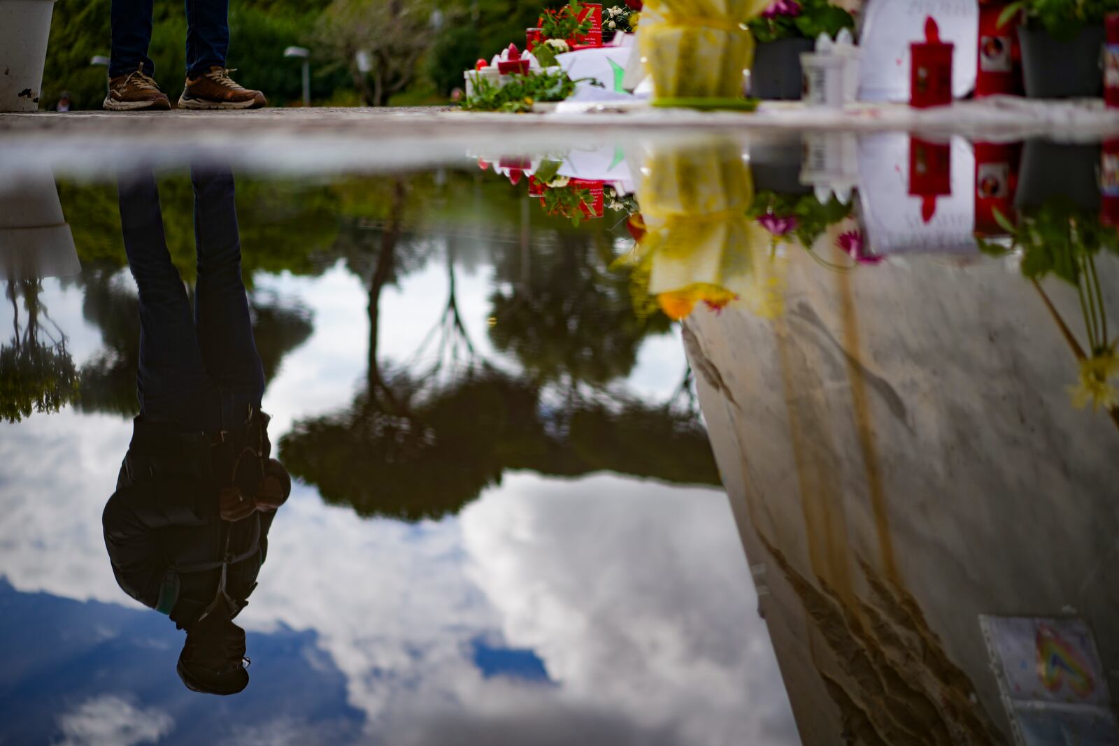 A man is reflected in a puddle in front of the Agostino Gemelli Polyclinic, in Rome, Thursday, March 13, 2025, where Pope Francis is hospitalized since Friday, Feb. 14. (AP Photo/Andrew Medichini)