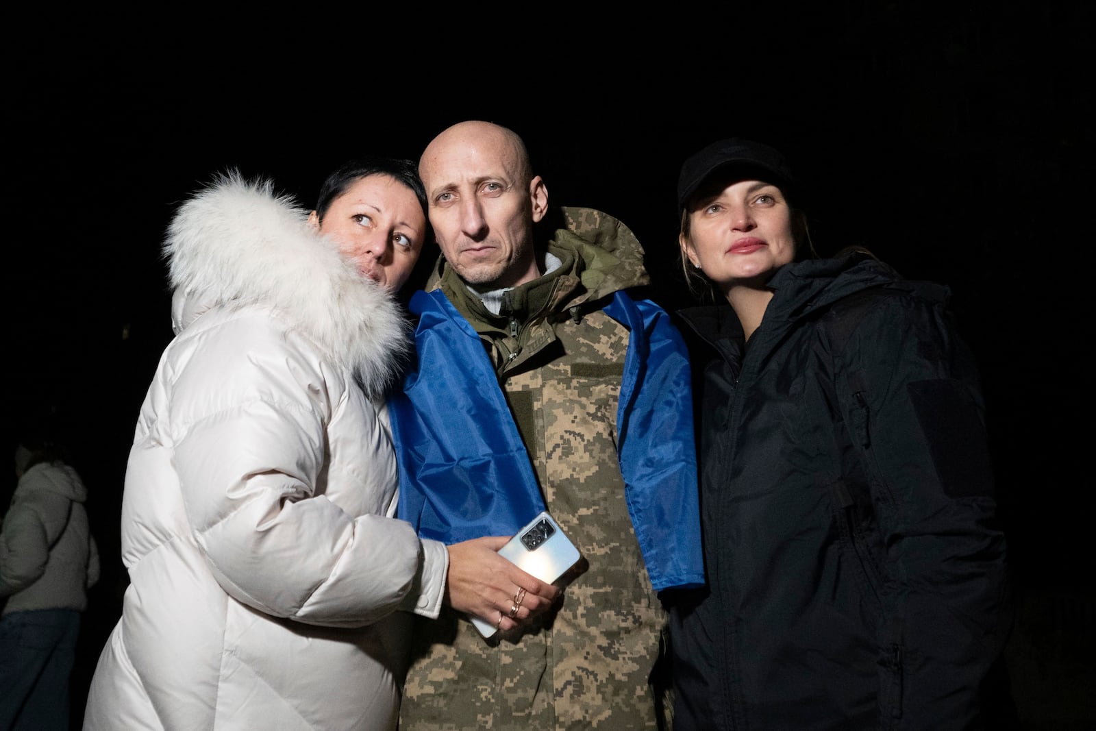 In this photo provided by the Press Service of the President of Ukraine on Oct. 19, 2024, a Ukrainian serviceman hugs his relatives after returning from captivity during a POWs exchange in an undisclosed location, Ukraine. (Press Service of the President of Ukraine via AP)