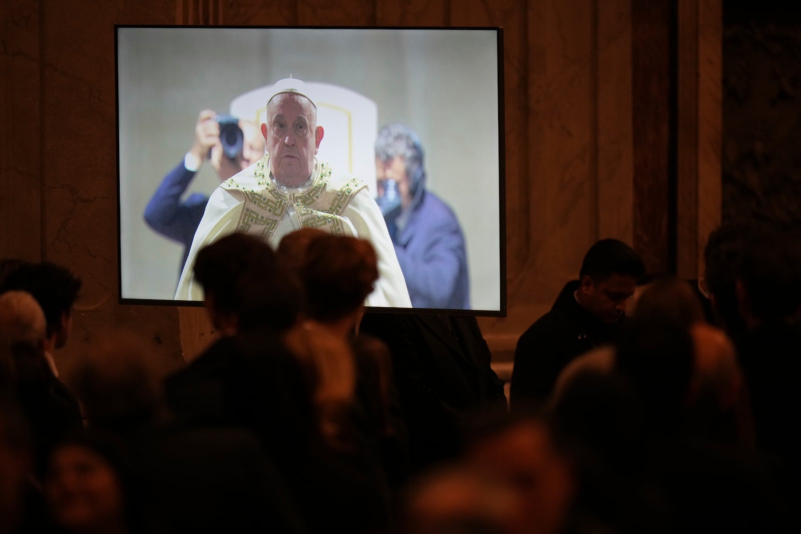 A giant monitor shows Pope Francis pausing before entering the holy door at the start of the Christmas Eve Mass in St. Peter's Basilica at The Vatican, Tuesday, Dec. 24, 2024, (AP Photo/Andrew Medichini)