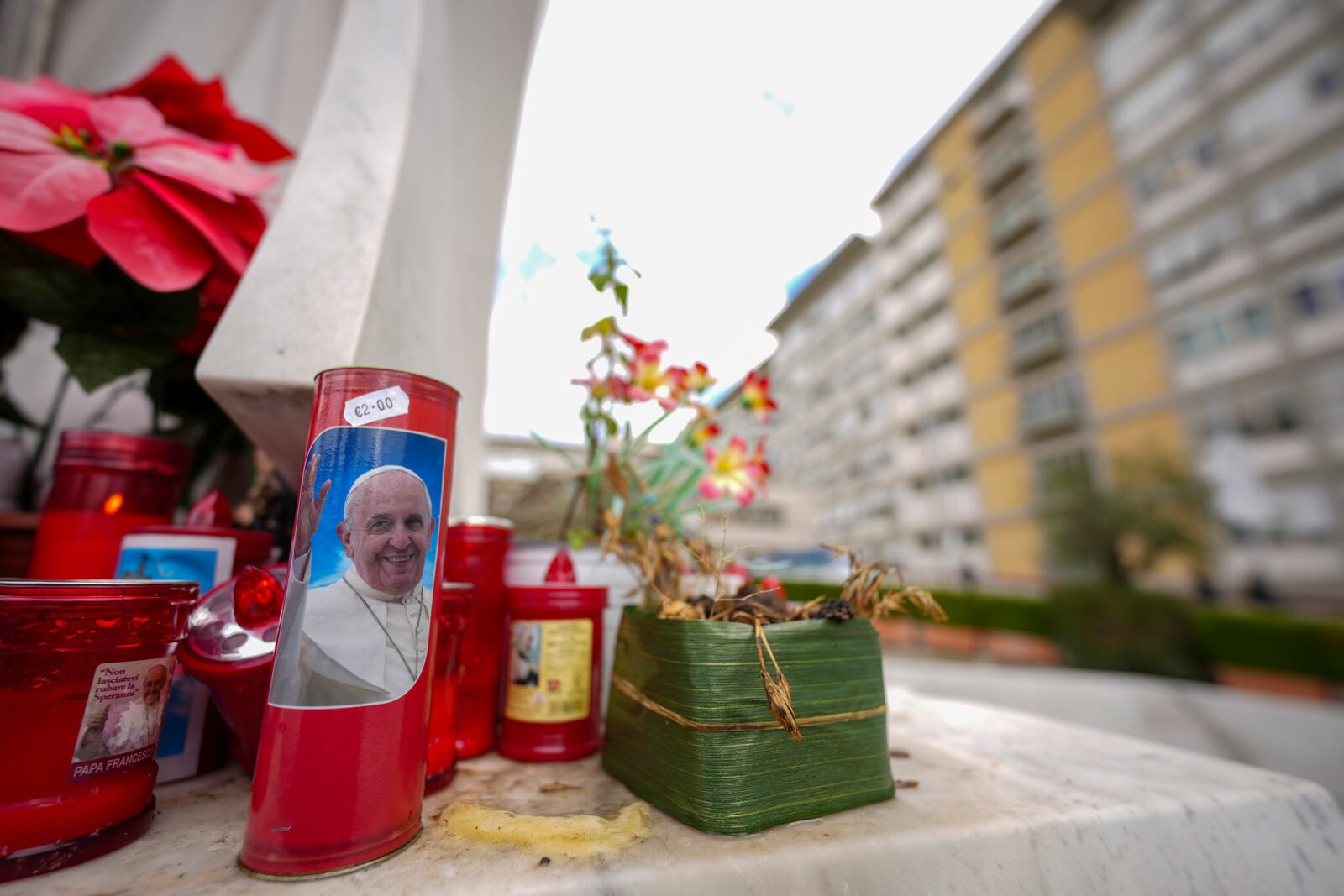 Candles, one showing a photo of Pope Francis, are seen in front of the Agostino Gemelli Polyclinic in Rome, Friday, Feb. 14, 2025, where Pope Francis has been hospitalized to undergo some necessary diagnostic tests and to continue his ongoing treatment for bronchitis. (AP Photo/Andrew Medichini)