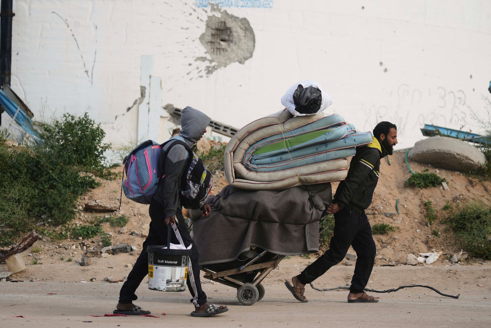 Displaced Palestinians, carrying their belongings, move away from the areas where the Israeli army is operating after Israel's renewed offensive in the Gaza Strip, on the outskirts of Beit Lahia, Thursday, March 20, 2025. (AP Photo/Jehad Alshrafi)