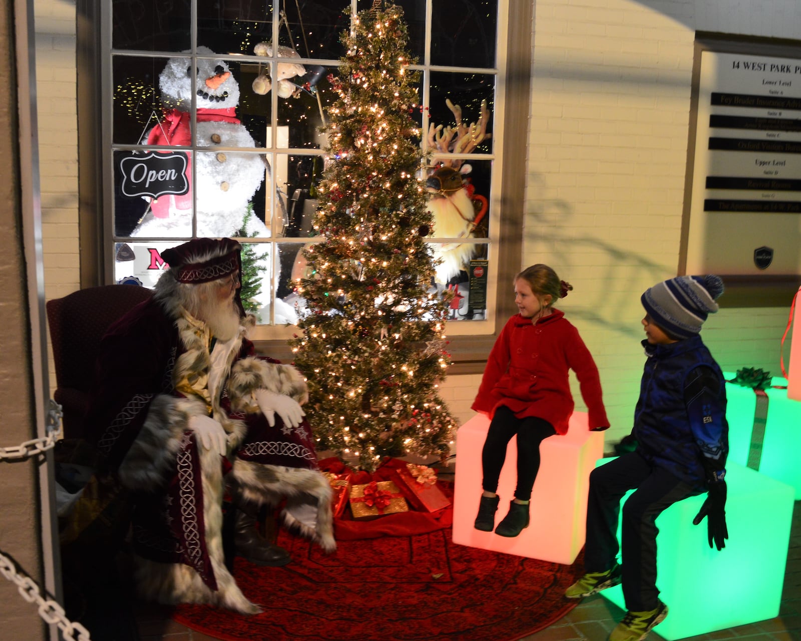 Santa Claus met with kids to hear their holiday wishes during the evening of the Holiday Festival. The visits were held outside in front of a festive window at Enjoy Oxford. CONTRIBUTED/BOB RATTERMAN