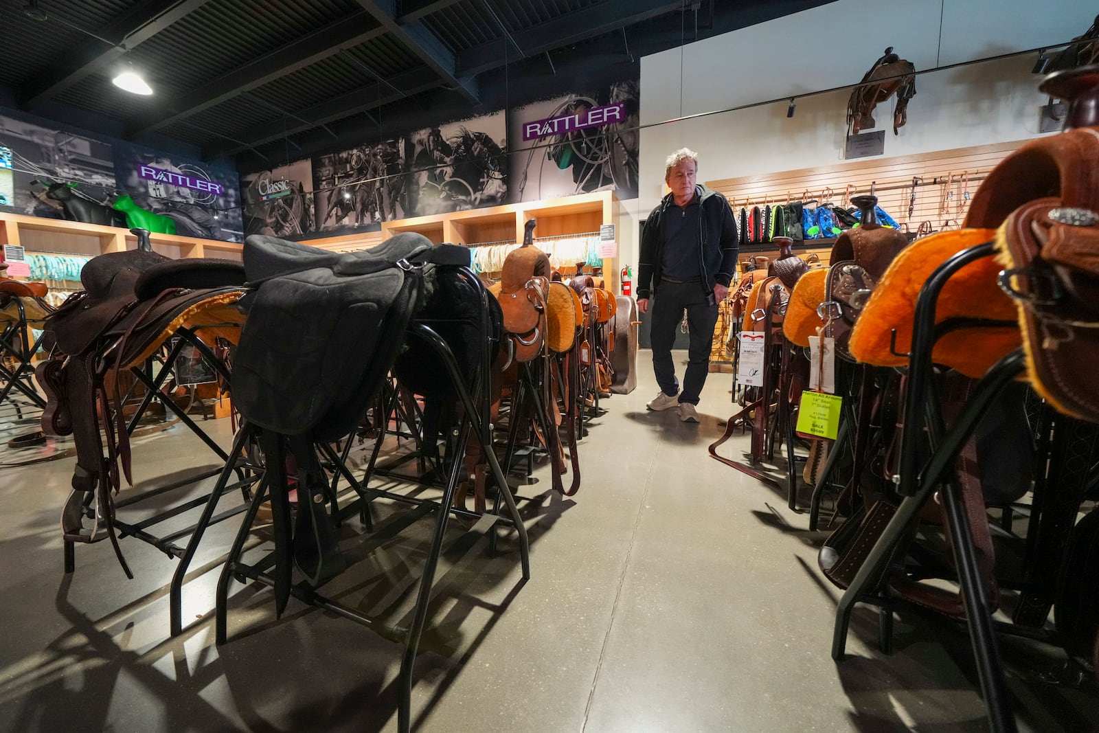 Chuck Carver, of Rutherfordton, N.C., looks at saddles at a supply store near the Oklahoma National Stockyards Tuesday, Jan. 14, 2025, in Oklahoma City. (AP Photo/Julio Cortez)