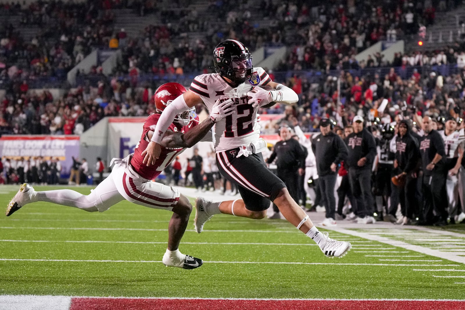 Texas Tech tight end Jalin Conyers (12) scores a touchdown past Arkansas defensive back Miguel Mitchell (16) during the first half of the Liberty Bowl NCAA college football game Friday, Dec. 27, 2024, in Memphis, Tenn. (AP Photo/George Walker IV)