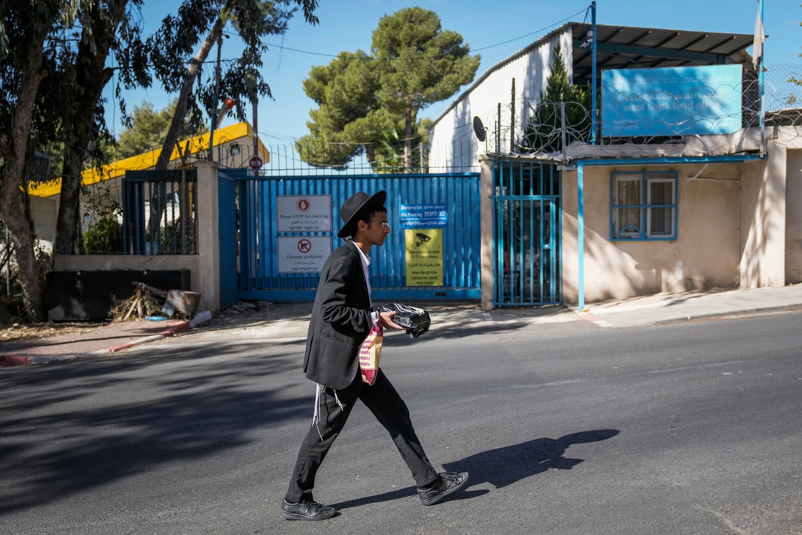 An ultra-Orthodox Jewish man walks past the east Jerusalem compound of UNRWA, the U.N. agency helping Palestinian refugees, Tuesday, Oct. 29, 2024. (AP Photo/Mahmoud Illean)