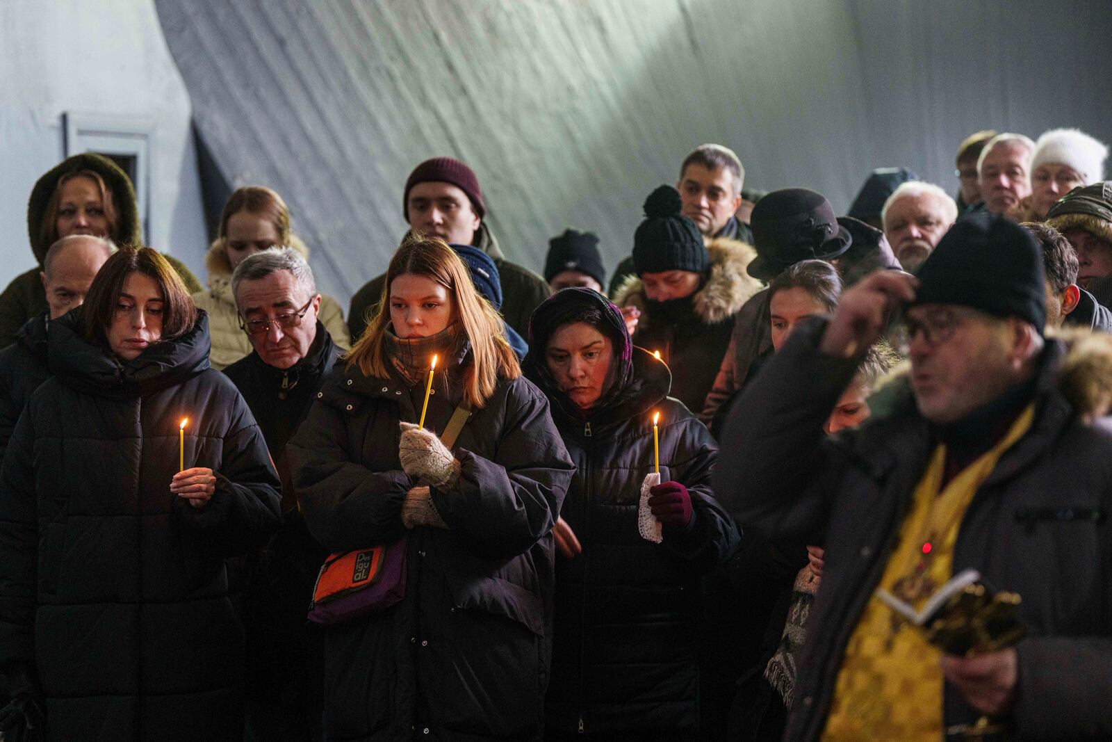 Relatives and friends hold candles during the funeral ceremony of neurobiologist Ihor Zyma and his wife, biologist Olesia Sokur, who were killed by a Russian strike on Jan. 1, in Kyiv, Monday, Jan. 6, 2025. (AP Photo/Evgeniy Maloletka)