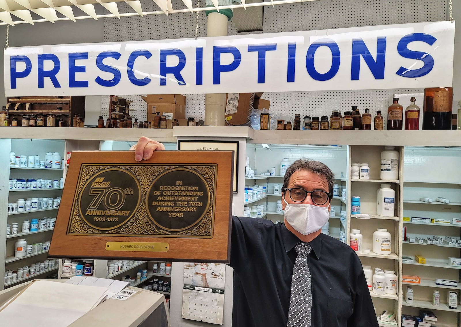 Pharmacist Jim Fescina shows some of the historic items on display in Hughes Pharmacy Wednesday, January 27, 2021. Hughes Pharmacy, a business that has been in Hamilton for over 100 years, will close its doors permanently on Saturday. NICK GRAHAM / STAFF