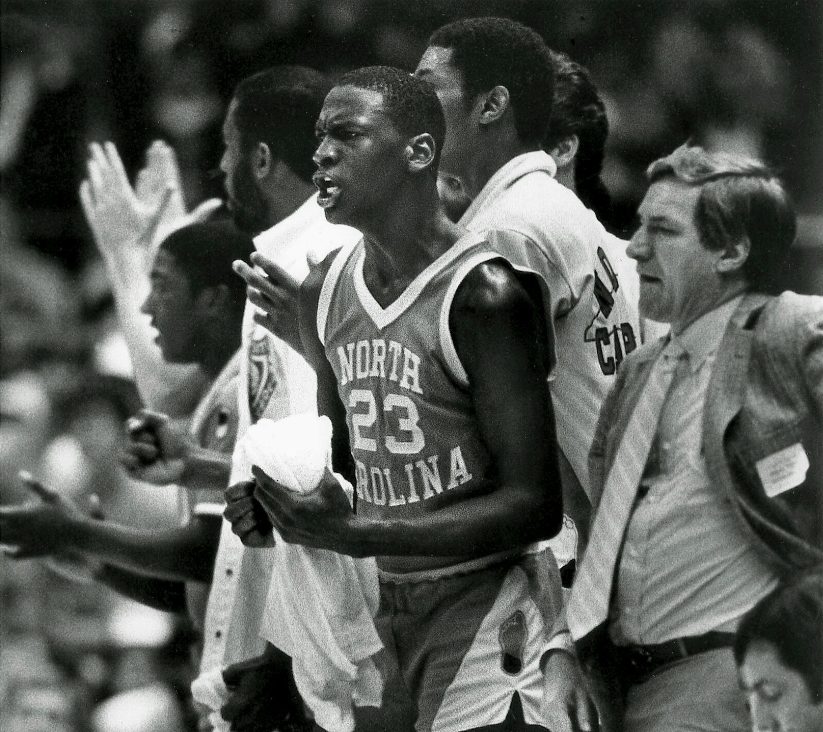 FILE - North Carolina's Michael Jordan (23) cheers from the bench as the Tar Heels wins another game for head coach Dean Smith, right, in Raleigh on Nov. 15 1983. (AP Photo/Bob Jordan, file)