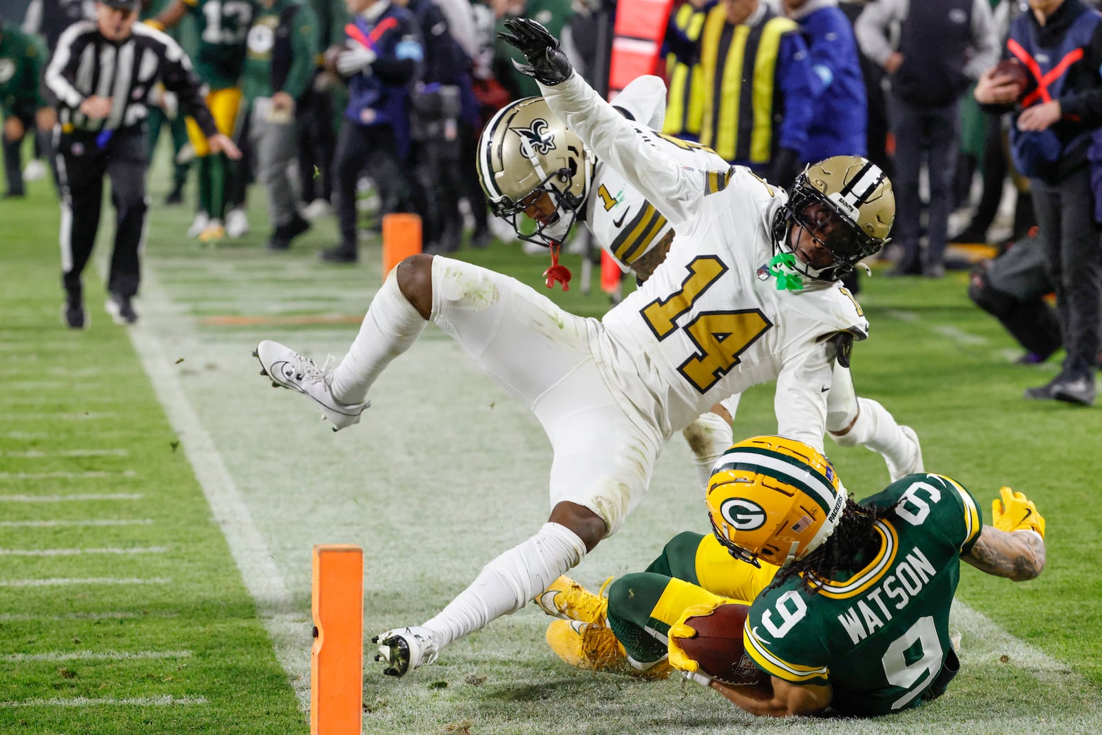 Green Bay Packers wide receiver Christian Watson (9) is knocked out of bounds by New Orleans Saints cornerback Kool-Aid McKinstry (14) during the first half of an NFL football game, Monday, Dec. 23, 2024, in Green Bay, Wis. (AP Photo/Mike Roemer)