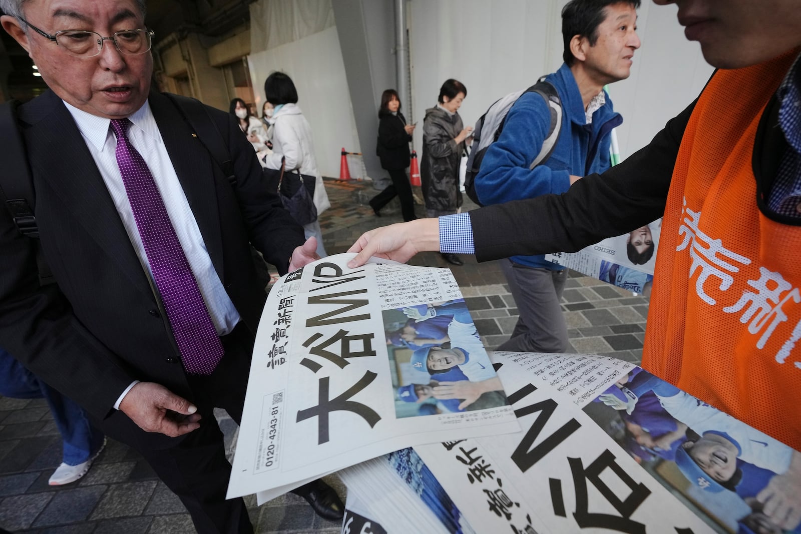 A staff member distributes an extra edition of the Yomiuri Shimbun newspaper reporting that Los Angeles Dodgers' Shohei Ohtani won his third Most Valuable Player award, Friday, Nov. 22, 2024, in Tokyo. (AP Photo/Eugene Hoshiko)