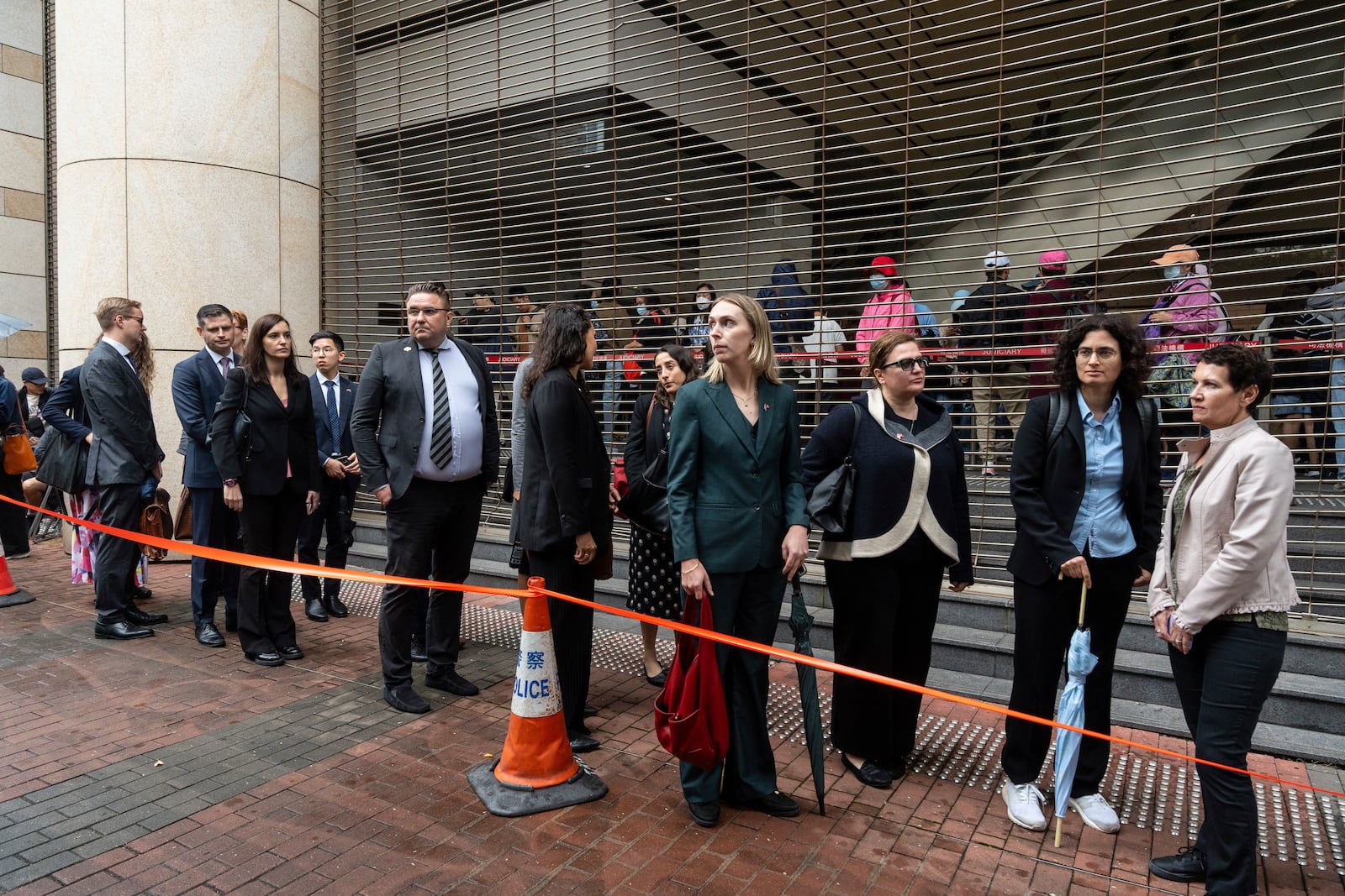 Representatives from various consulates wait in line outside the West Kowloon Magistrates' Courts in Hong Kong Tuesday, Nov. 19, 2024, ahead of the sentencing in national security case. (AP Photo/Chan Long Hei)