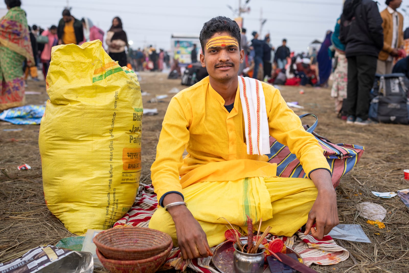 Hindu priest Anuj Kumar Tiwari, who puts sacred marks on devotees' foreheads, sits at his stall at the confluence of the Ganges, the Yamuna, and the Saraswati rivers during the 45-day-long Maha Kumbh festival in Prayagraj, India, Tuesday, Jan. 14, 2025. (AP Photo/Ashwini Bhatia)