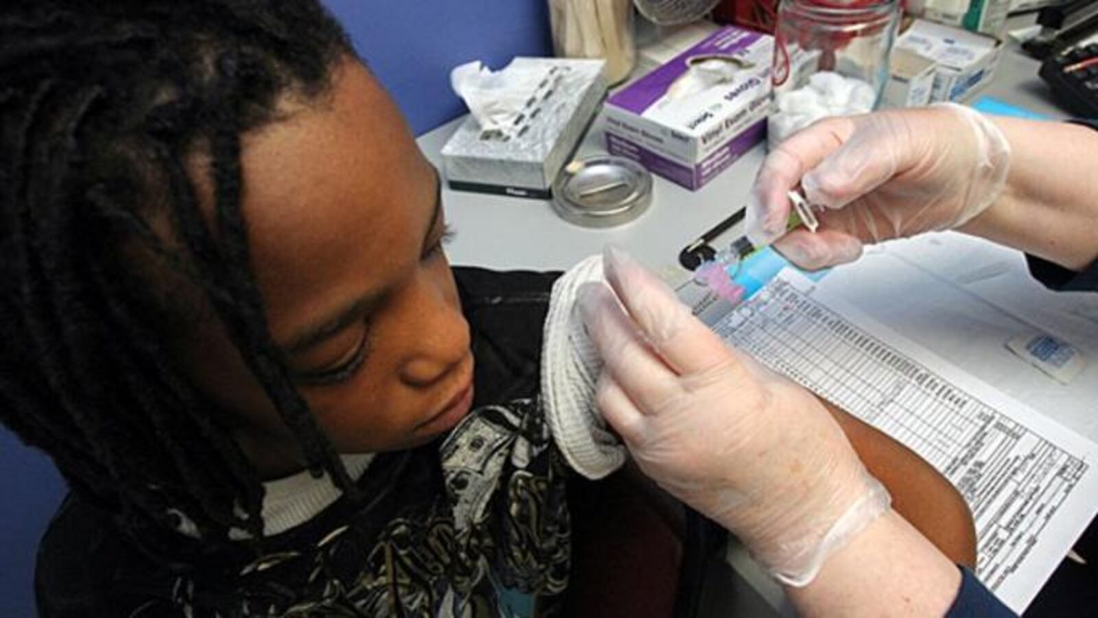 Fay Bishop gives Remondo Swinney, 12, a Tdap shot at the T.O. Vinson Health Center in Decatur, Georgia.