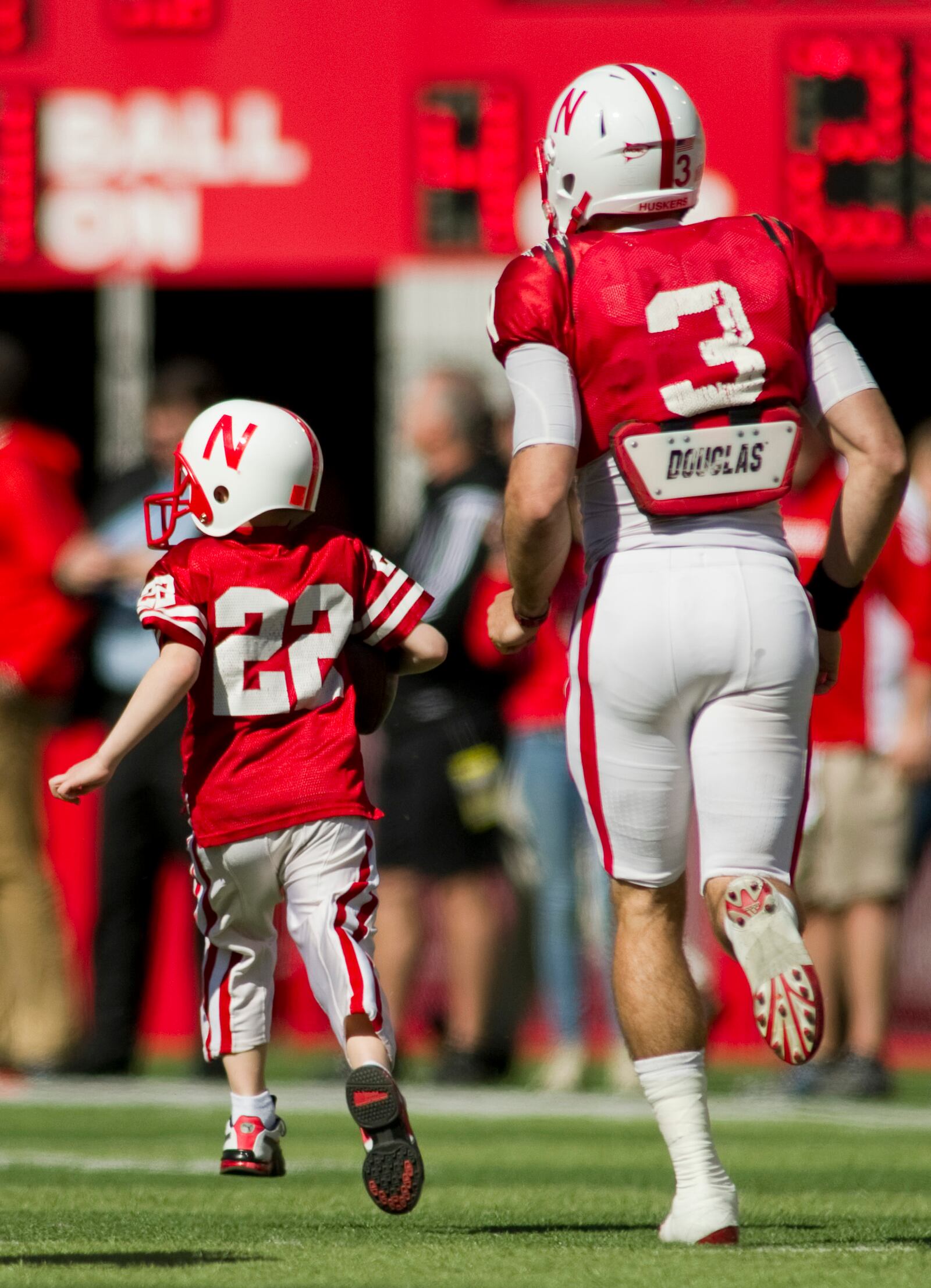 FILE - Nebraska's Taylor Martinez (3) guides Jack Hoffman, then 6, of Atkinson, Neb., down the field for his touchdown play during a special segment dedicated to Hoffman during the second half of the Red-White spring NCAA college football game at Memorial Stadium in Lincoln, Ne., April 6, 2013. (AP Photo/Lincoln Journal Star, Matt Ryerson, File)