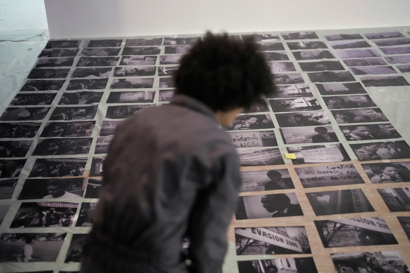 An assistant of French street artist Shuck One places archive images during the preparation of the exhibition "Paris Noir", at the Centre Pompidou Museum, in Paris, Tuesday, Feb. 18, 2025. (AP Photo/Thibault Camus)