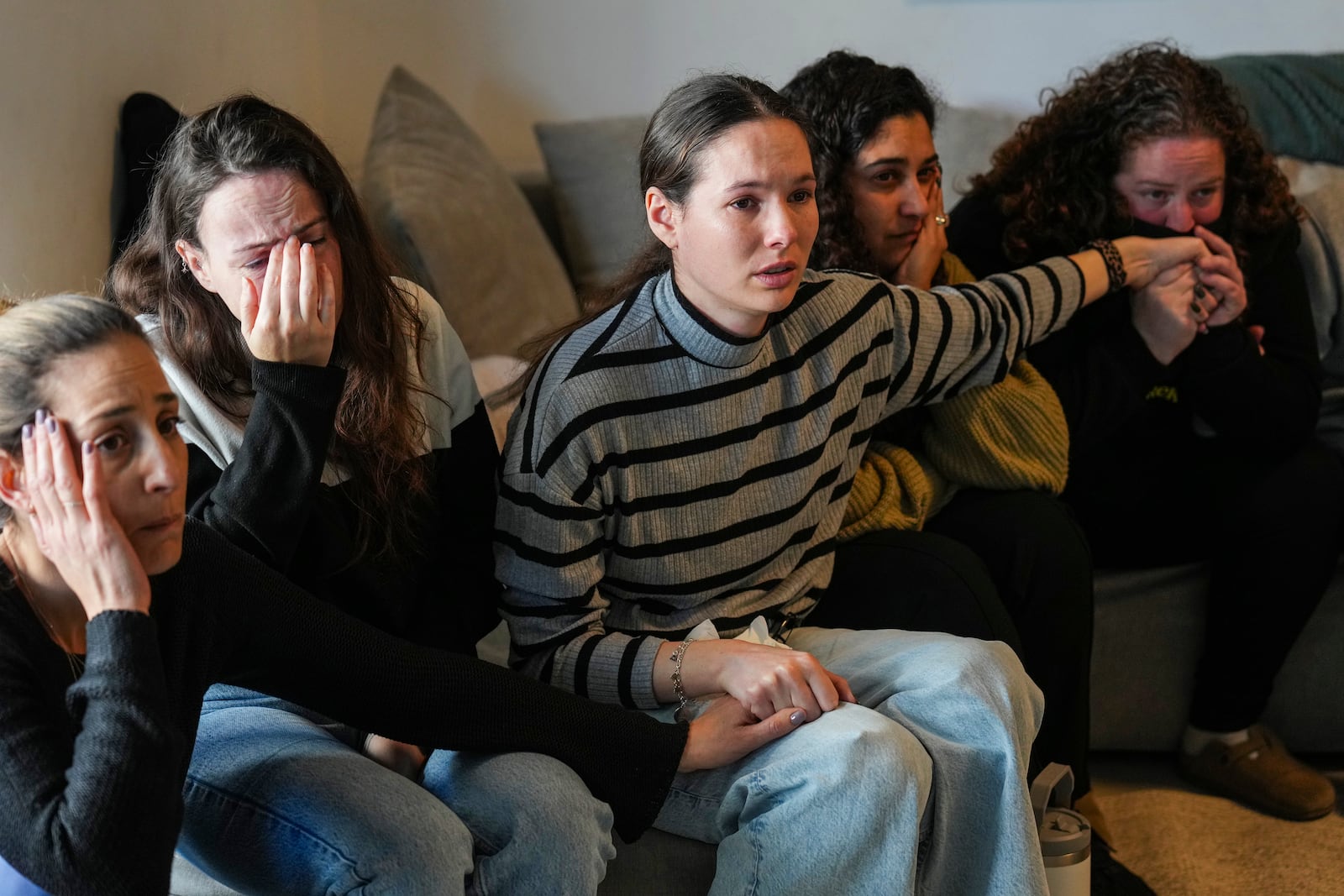 Freed hostage Shani Goren, right, and friends of Israeli hostage Arbel Yehoud react as they watch the broadcast of her being released from Hamas captivity, in Carmei Gat, southern Israel, Thursday, Jan. 30, 2025, as part of the Israel-Hamas ceasefire deal. (AP Photo/Ariel Schalit)