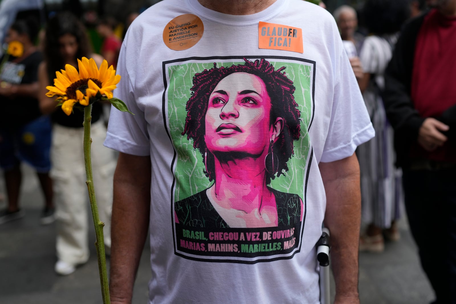 An activist wearing a T-shirt with the image of former city councilwoman Marielle Franco attends a rally prior to the trial for Franco's alleged killers, outside the Court of Justice, in Rio de Janeiro, Wednesday, Oct. 30, 2024. (AP Photo/Silvia Izquierdo)