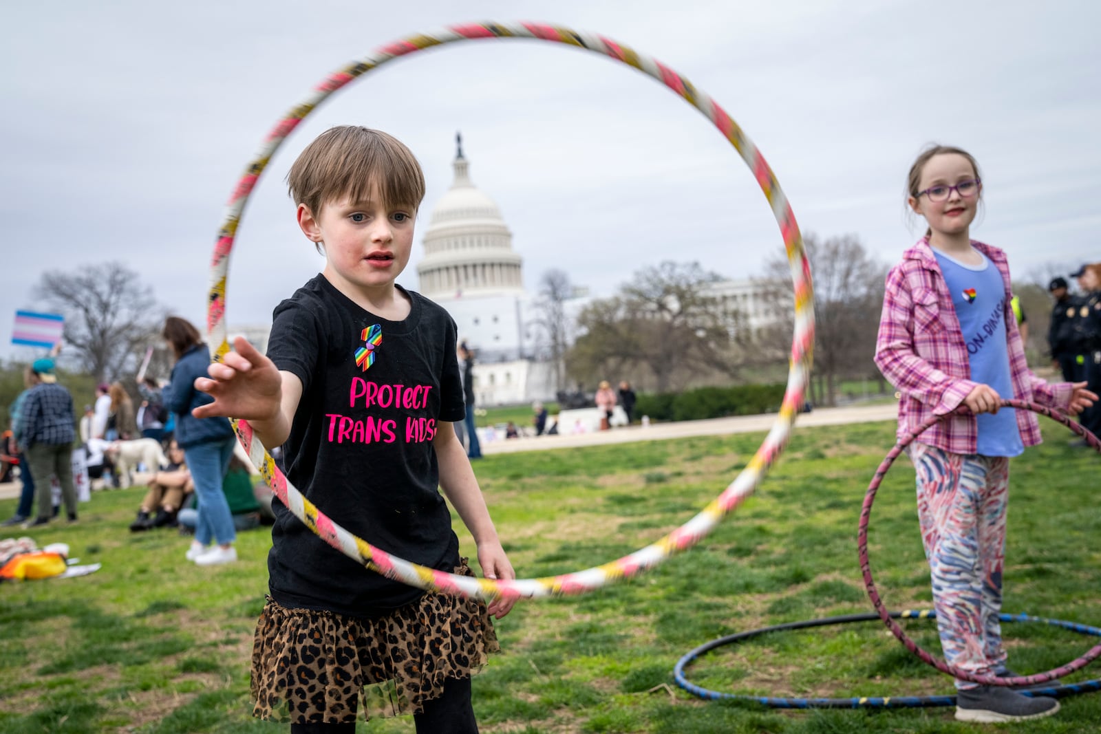 FILE - Mac Gordon Frith, 6, left, who is here supporting his sibling, Caleta Frith, 9, right, who is non-binary, plays with a hula hoop during a rally on the Transgender Day of Visibility, Friday, March 31, 2023, by the Capitol in Washington. (AP Photo/Jacquelyn Martin, File)