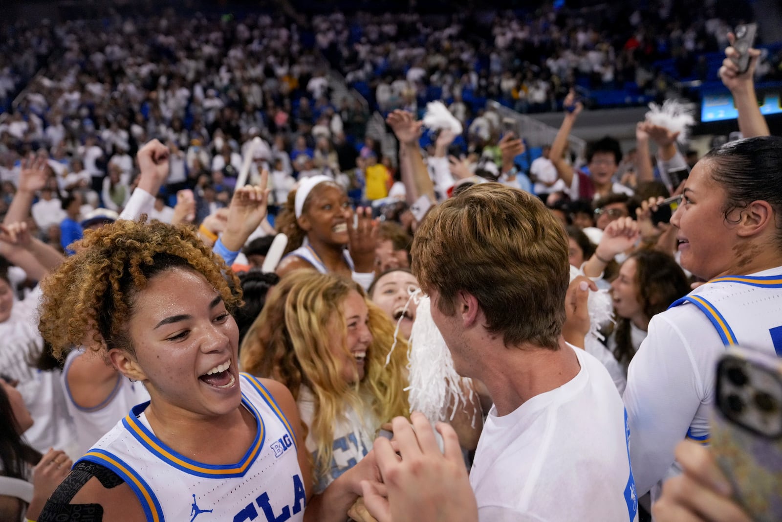 UCLA guard Kiki Rice, left, celebrates with fellow students and teammates after an NCAA college basketball game against South Carolina, Sunday, Nov. 24, 2024, in Los Angeles. (AP Photo/Eric Thayer)