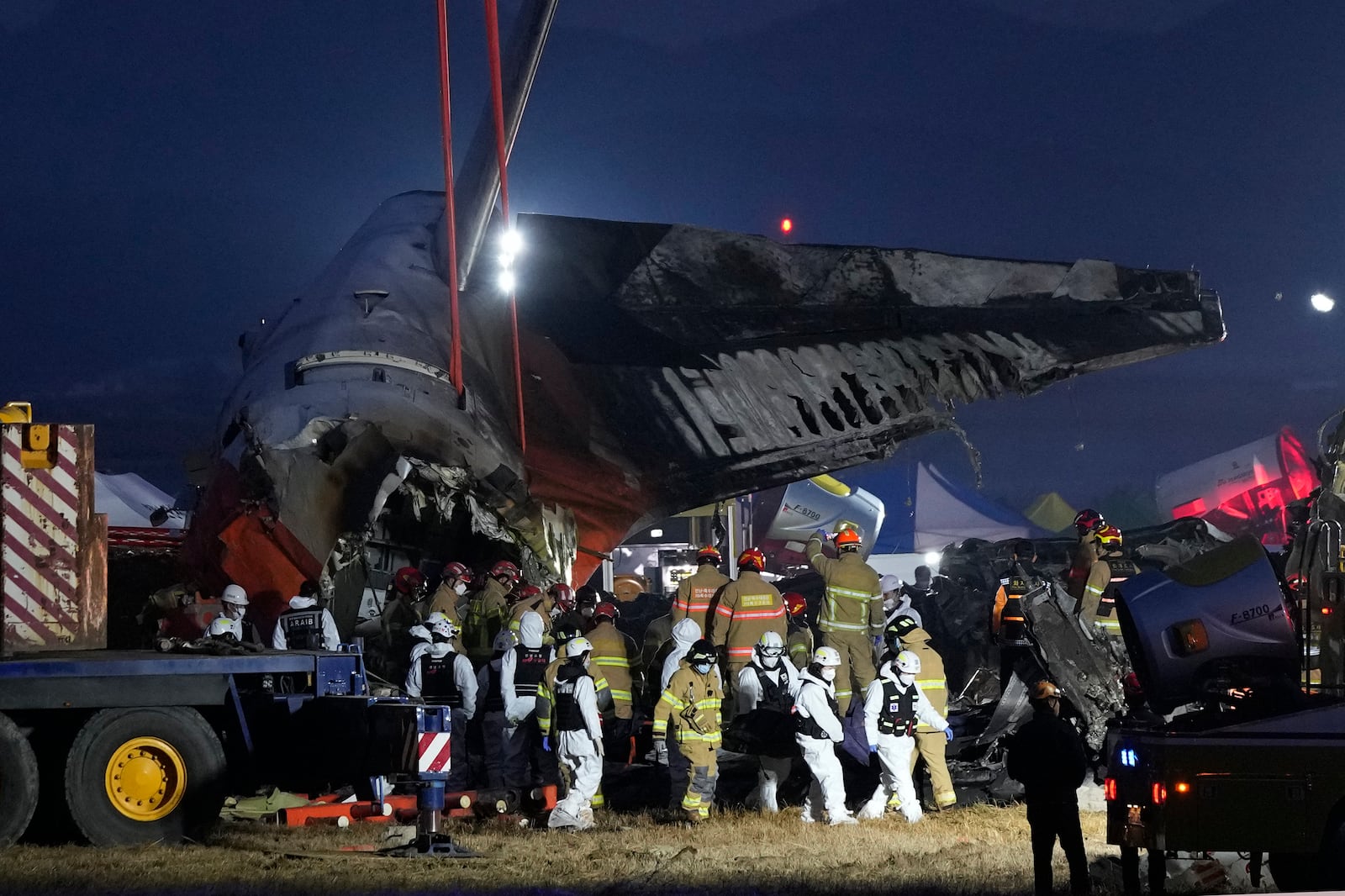 Rescue team carry the body of a passenger at the site of a plane fire at Muan International Airport in Muan, South Korea, Sunday, Dec. 29, 2024. (AP Photo/Ahn Young-joon)