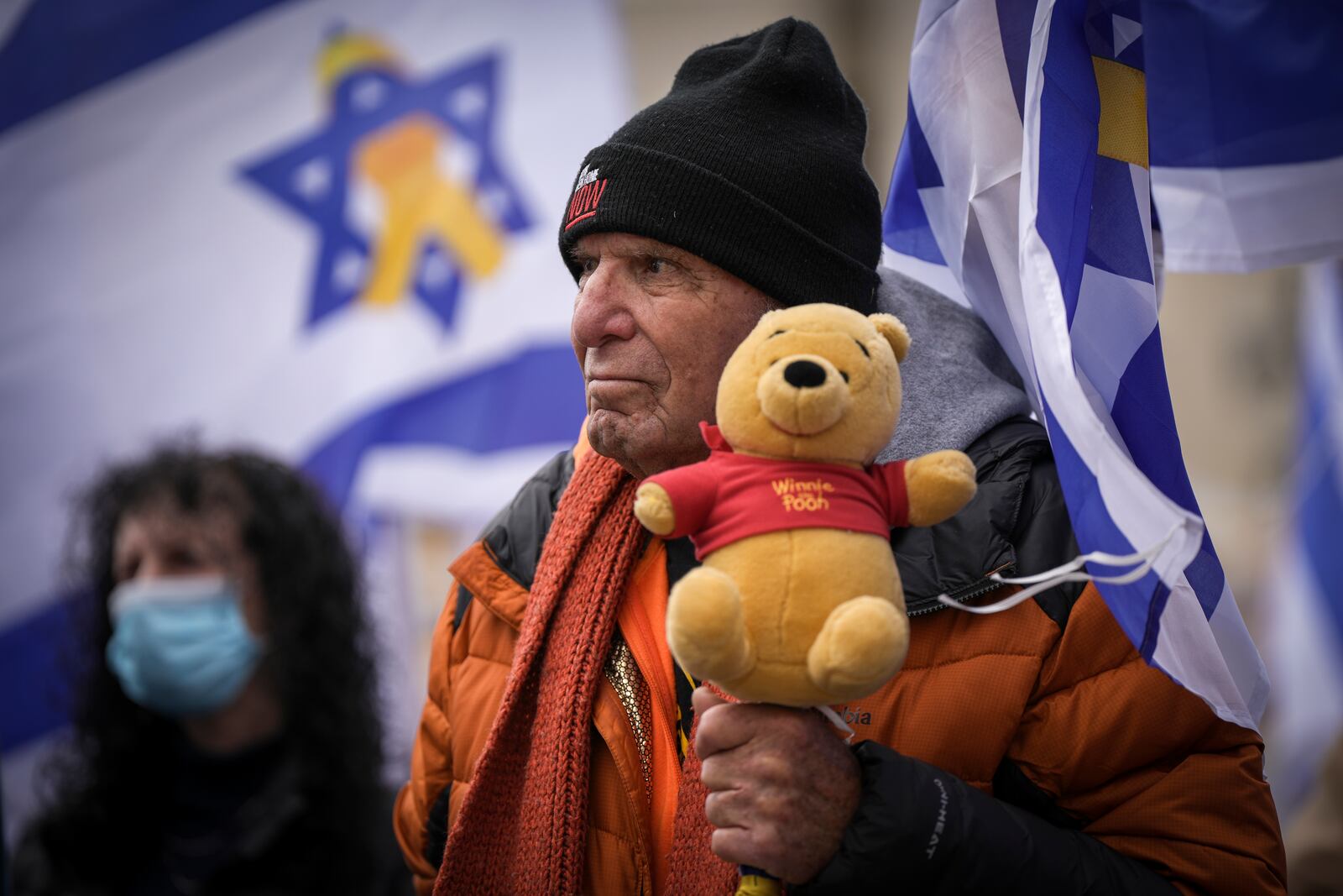 A man holds a teddy bear at the so-called 'Hostages Square' in Tel Aviv, Israel, Thursday, Feb. 20, 2025, after the bodies of four Israeli hostages, including a mother and her two children, were handed over by Palestinian militant groups to the Red Cross in Gaza. (AP Photo/Oded Balilty)