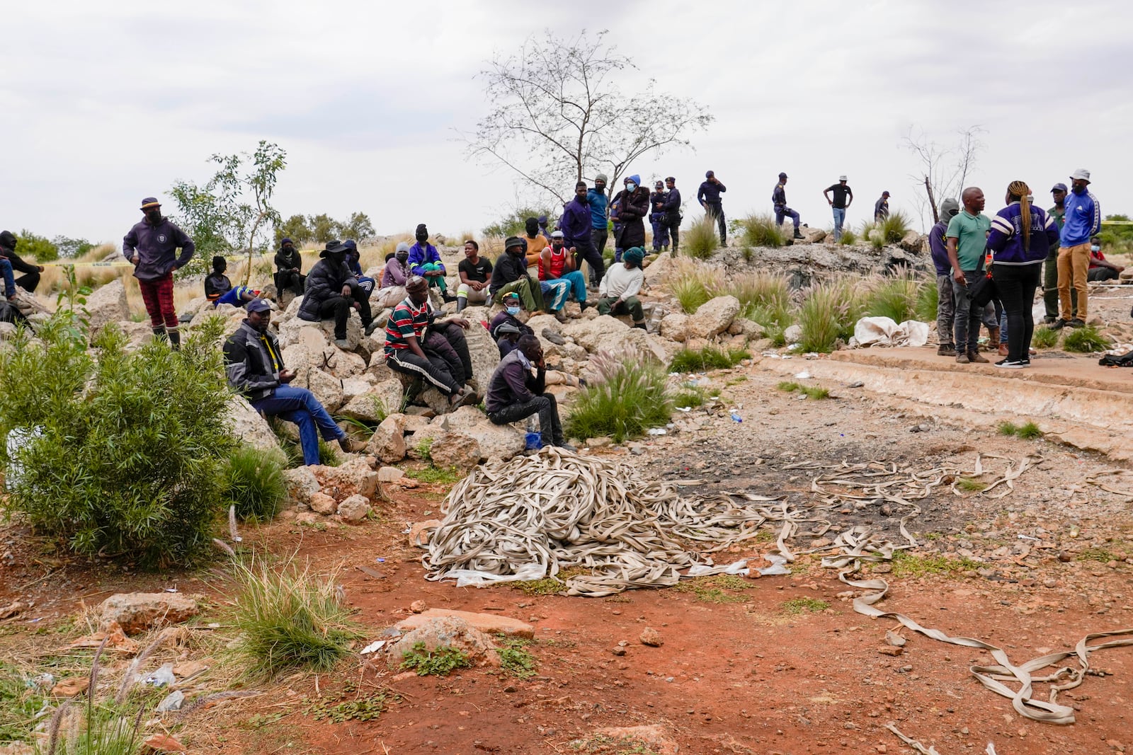 Volunteer rescuers sit by the opening of a reformed gold mineshaft where illegal miners are trapped in Stilfontein, South Africa, Friday, Nov. 15, 2024. (AP Photo/Denis Farrell)