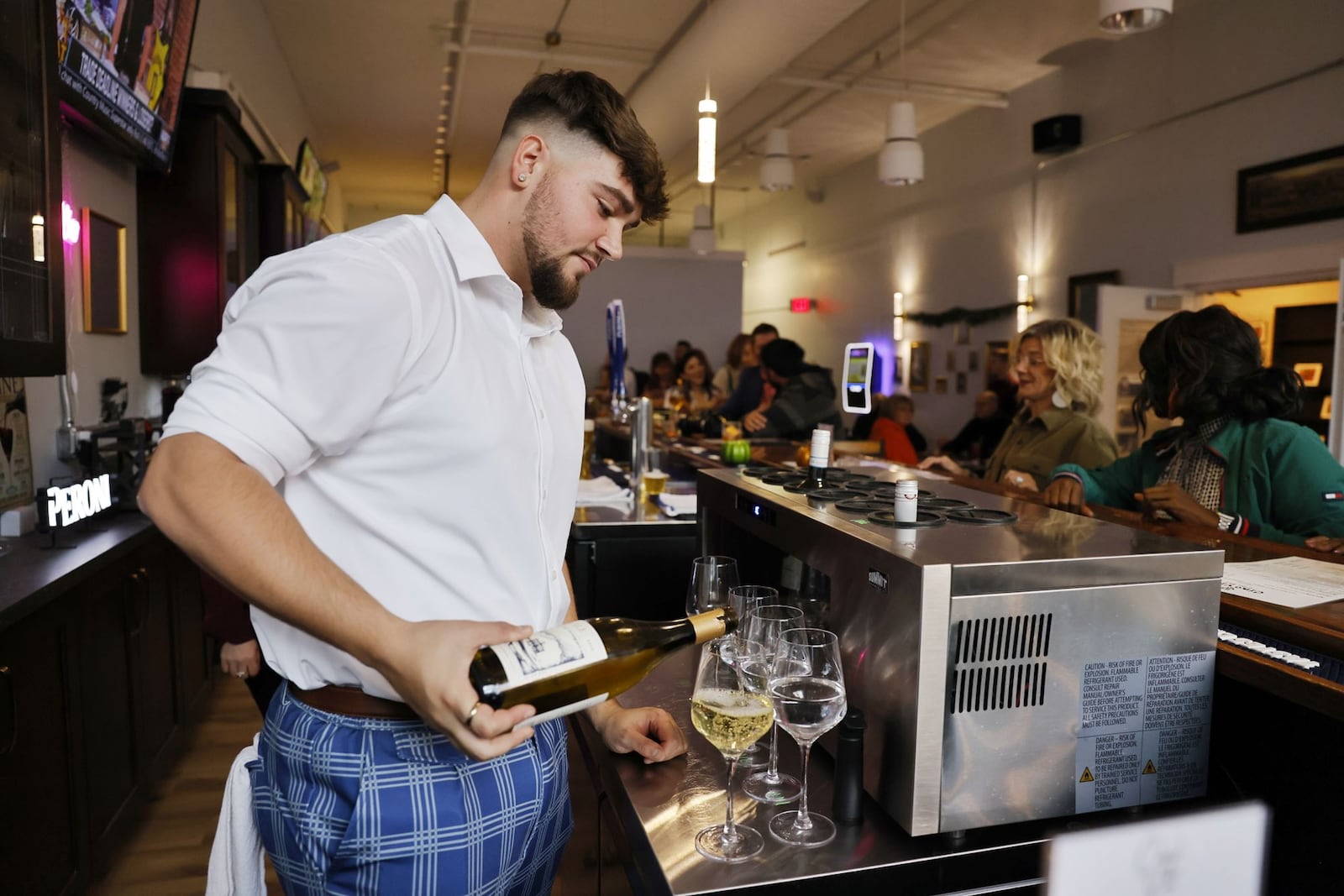 Kaden Kimbrell pours a glass of wine at Ciao Vino wine bar after they opened Thursday, Nov. 7, 2024 with ribbon cutting and grand opening on High Street in Hamilton. NICK GRAHAM/STAFF