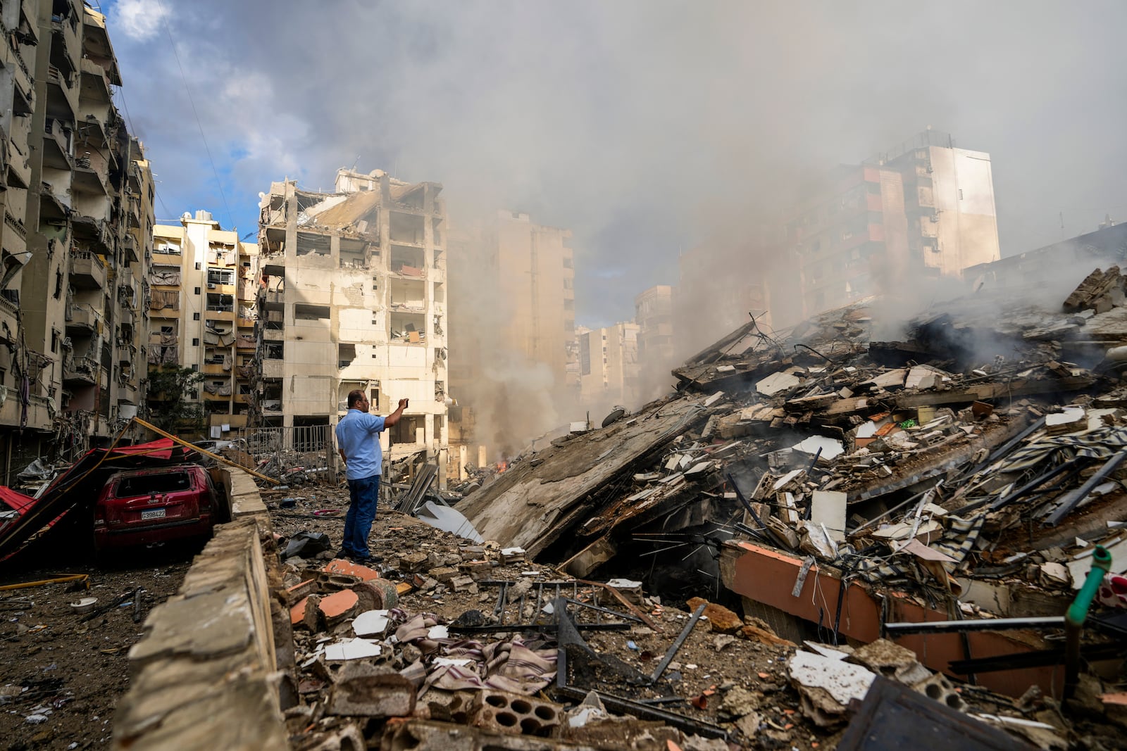 A man documents the damaged buildings at the site of an Israeli airstrike in Beirut's southern suburb, Lebanon, Tuesday, Oct. 1, 2024. (AP Photo/Hassan Ammar)