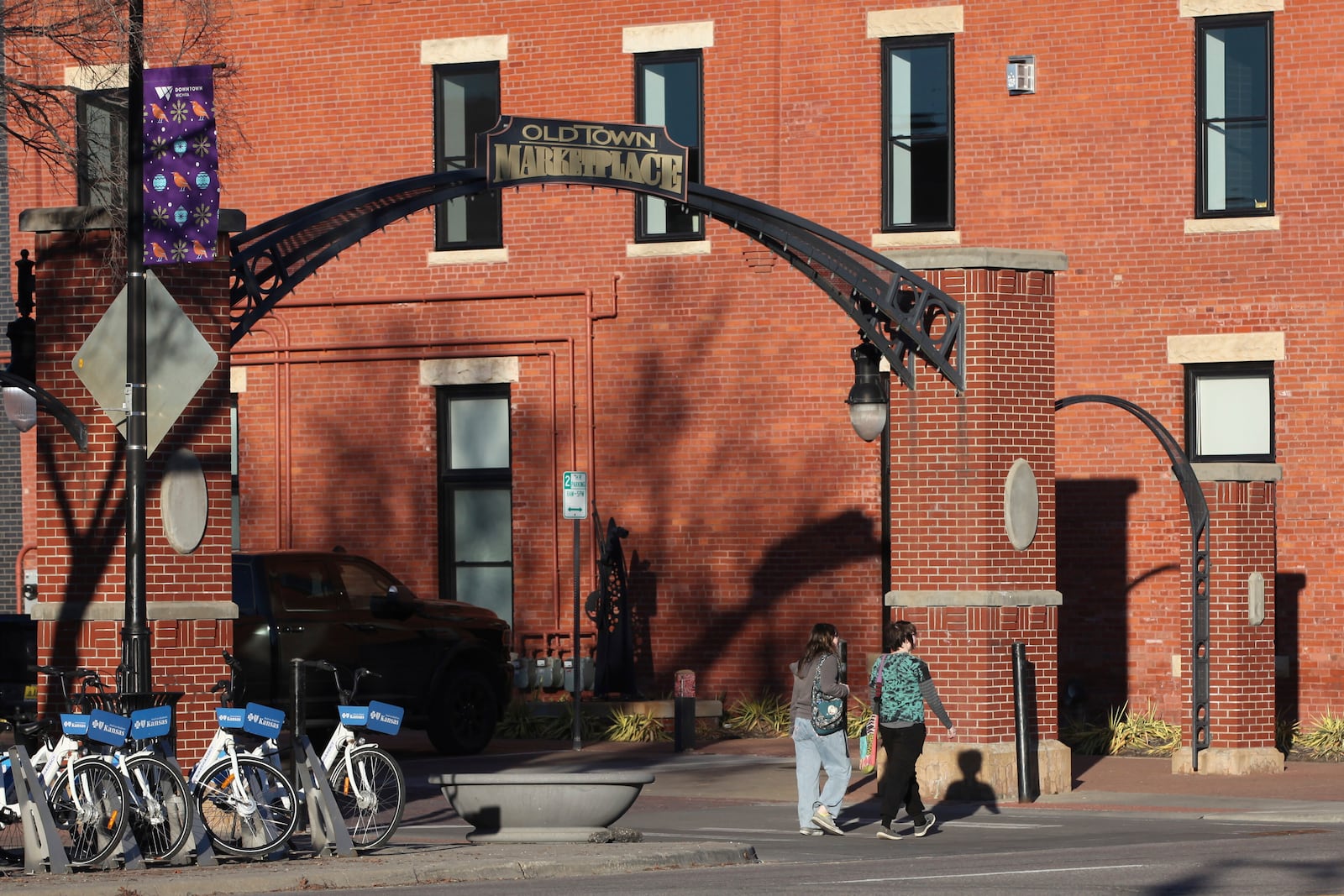 Two visitors walk past an entrance to the Old Town Marketplace, Friday, Jan. 31, 2025, in downtown Wichita, Kansas. (AP Photo/John Hanna)